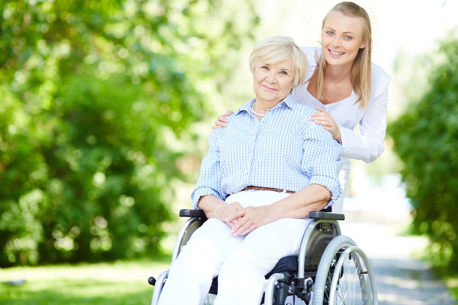 caregiver-pushing-senior-woman-wheelchair_1098-3013