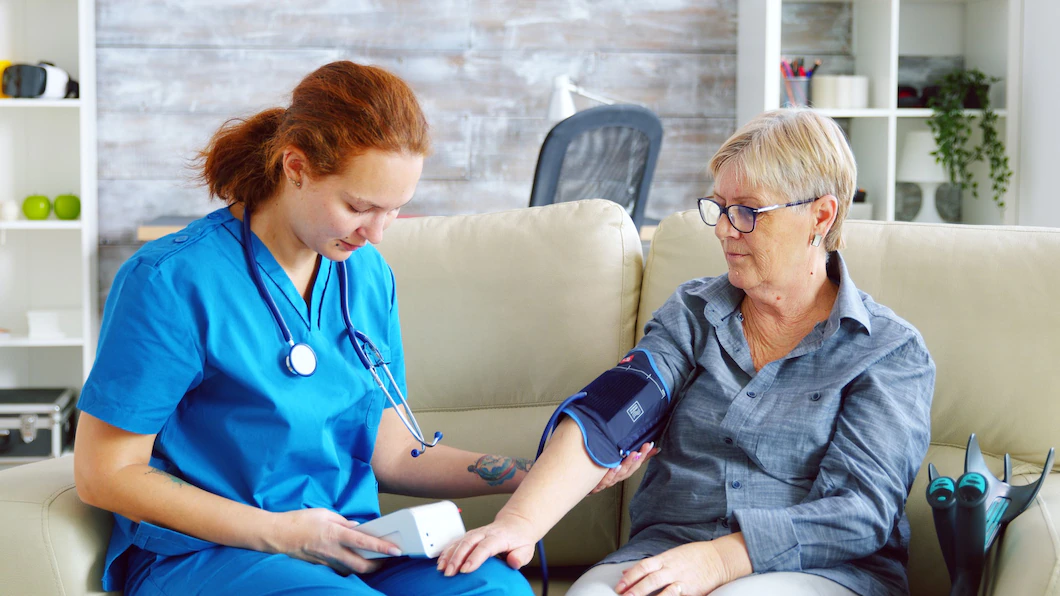 female-doctor-taking-blood-pressure-senior-woman-nursing-home-sitting-sofa_482257-20666