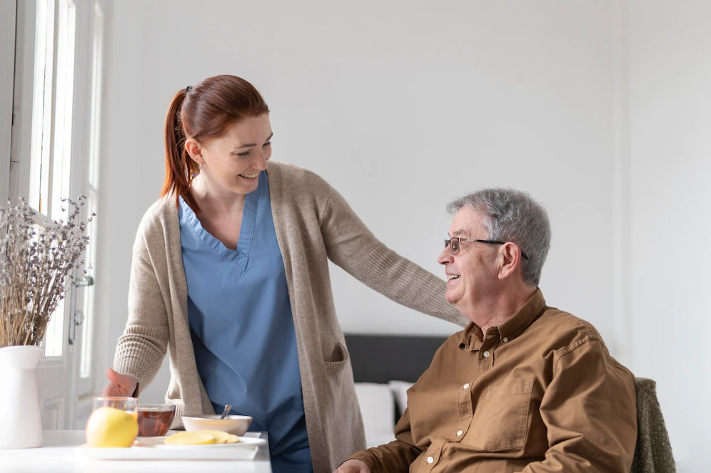 At home caregiver assisting elderly man